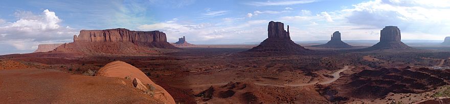 Panorama of rock formations at Monument Valley in Arizona.  A red, barren, desert landscape with several mesas and gigantic, unusual rock formations.