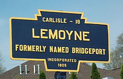 A keystone shaped road marker containing the distance to Carlisle of 18 miles, the name Lemoyne, the description of formerly named Bridgeport, and incorporated 1905.
