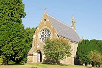 Tall stone-built church with rose window and bellcote