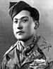 Head and shoulders of a young man with a garrison cap tilted over his right ear wearing a scarf tied around his neck and a military jacket with three ribbon bars and a pin on the left breast. Written over the lower right of the photo are the words "Your pal always, Frank".