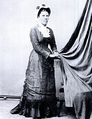 A woman standing in 1890s dress