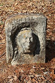 Single concrete gravestone with female face