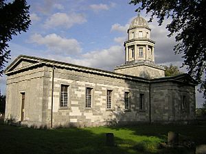 A neoclassical church seen from an angle with the nave in the foreground and towards the back a lantern with a dome
