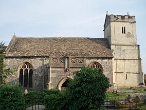 A stone church seen from the north with a central doorway surmounted by a pierced parapet, and to the right a battlemented tower