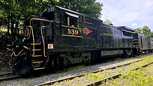 A GE B32-8 in the Western Maryland "Fireball" livery and the number 539 sits idle on the woods-lined tracks leading into Frostburg, MD.