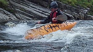 Kayaker surfing on the river Orchy Scotland