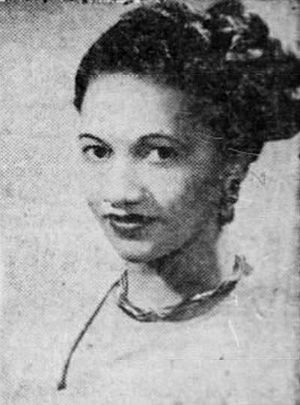 A portrait of an African-American woman with an elaborate hair bun wearing a braided choker necklace and a v-necked top.