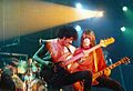 Phil Lynott plays bass guitar next to a guitarist