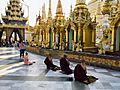 A nun and group of monks praying before idols in Myanmar