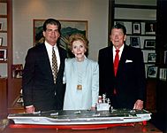 The Reagans and Newport News Shipbuilding chairman and CEO William Frick standing behind a model of the aircraft carrier USS Ronald Reagan, 1996