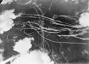 A picture of a piece of sky with several clouds and many condensation trails caused by many aircraft. Each trail curves around the other indicated an air battleItalic text
