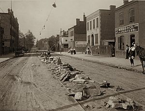 Children pose on rocks and stones piled on tracks during streetcar strike of 1900, looking north on Fifteenth from O'Fallon Street