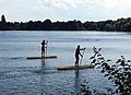 Two lifeguards of the German DLRG patrolling bathing area of a lake on stand-up paddling boards