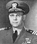 Head and shoulders of man in his forties, wearing glasses and a World War II style U.S. naval officer's uniform