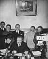 Soviet Foreign Minister Vyacheslav Molotov signs the Molotov–Ribbentrop Pact. Behind him stand German Foreign Minister Joachim von Ribbentrop and Soviet Premier Joseph Stalin.