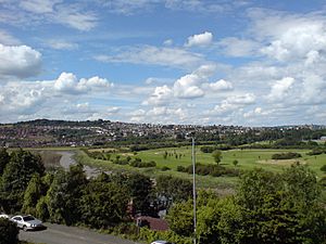 A photograph taken from a house window on Caerleon Road in St Julians. The view crosses the river Usk and in the distance is the Caerleon Golf Club, and behind it, the settlement of Caerleon, on the hill with rows of houses visible. At the far right are the visible buildings of Caerleon Comprehensive School and its sports facilities.