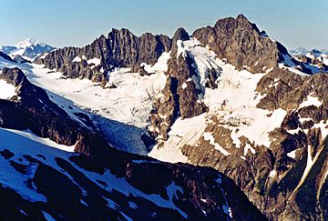 A large, rugged mountain rises above a snowy ridge