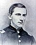Head and shoulders of a young white man wearing a military jacket with rectangular patches atop each shoulder.