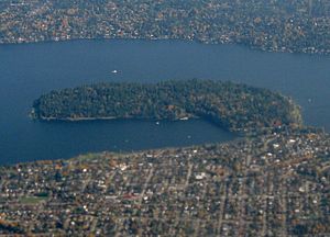 A forested peninsula surrounded by a lake and urban neighborhoods