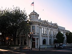 Image of front corner of Bank of San Mateo County building with flag waving in the wind on top.