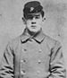 Head and torso of a young white man wearing a forage cap and a heavy double-breasted coat with two columns of buttons down the chest.