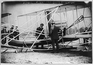 Wilbur Wright examining canoe attachment to aeroplane before 1st flight over water (3b25549u)