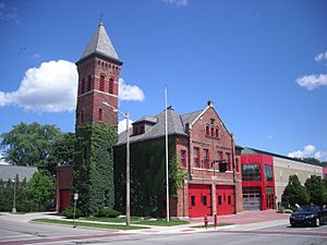 Brick fire station with tower and ivy growing on building