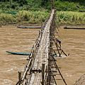 Wooden footbridge in Luang Prabang with a worker busy at its consolidation