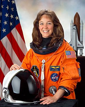 A smiling brunette white woman in her orange space suit