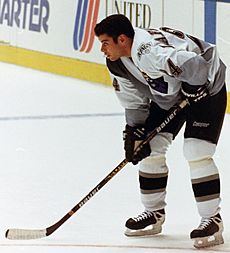 hockey player in white jersey holding hockey stick.