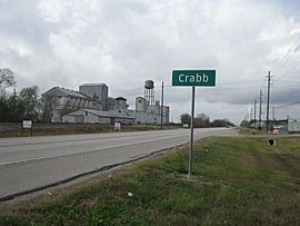 Crabb road sign on FM 762 looking west with disused grain elevator on left and businesses on the right