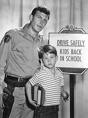 Man and boy standing next to a school drive safely sign