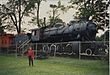 A woman standing in front of an antique steam locomotive