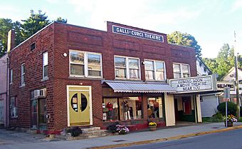 A two-story brick building with a rectangular facade and flat roof. A sign in the middle of the top of the building says "Galli-Curci Theatre". The ground floor has a storefront with dressed mannequins and a triangular marquee saying "Coming Soon: A Movie Theatre Near You" on the right.