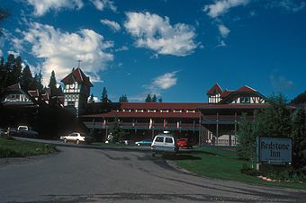 An ornate two-story building with a central clock tower and red roof in the rear of the left side of the image. On the right is a large sign in the foregrounds with "Redstone Inn" in large gothic letters, "Historic Landmark" in smaller type above it, and "Restaurant & Bar" below