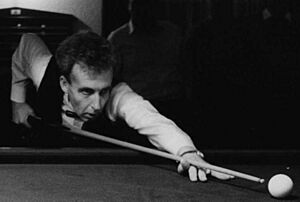 Upper-body shot of Terry Griffiths, a white middle-age man wearing a suit, playing snooker.