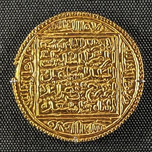 A round gold coin with a square pattern and Arabic calligraphy