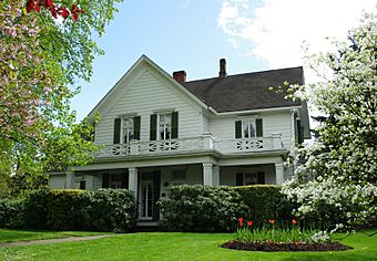 Photograph of the Cornelius House, a two-story, gabled house with flower gardens in front