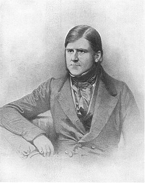 Black and white image of a seated man from the waist up.  He is dressed in a nineteenth century suit, clean shaven and looking to his right.