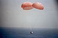 Spaceship descends over ocean with parachutes