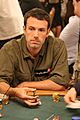 Ben Affleck holds chips while sitting at a poker table