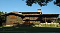 Photograph of the David B. Gamble House across its front lawn. It is a large house with wooden siding and trim presenting a very rustic feel.