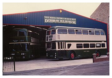 A double deck bus in front of a large iron clad garage