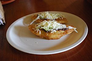 Fried empanadas with cheese, beans and lettuce on top