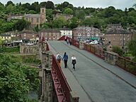 Pedestrians walking over a bridge with red-brown hand rails