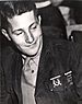 Head of a young man in a military jacket and tie, looking down and to the right