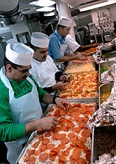 US Navy 070406-N-2959L-756 Members of USS Ronald Reagan (CVN 76) First Class Association prepare and put toppings on pizzas in the galley as part of a special dinner prepared for the crew