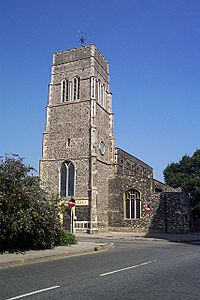 A tall flint tower with the body of the church extending beyond it