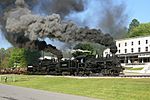 A locomotive on railroad tracks billowing black smoke.