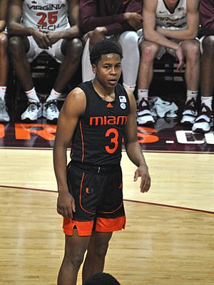 Moore standing in a Black Miami uniform in front of benches.